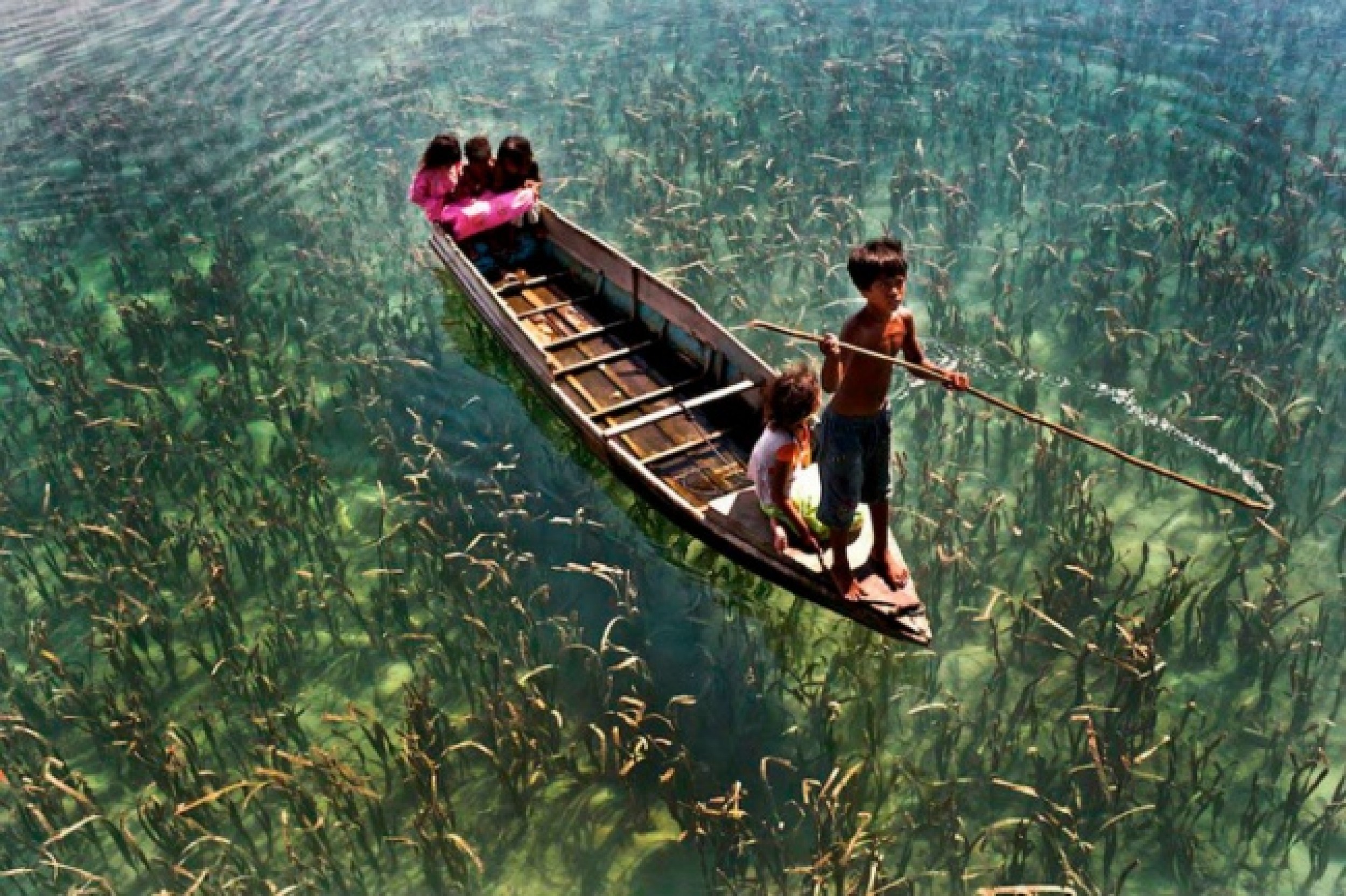 Трудно поверить. Озеро в Сабахе, Малайзия. Дети катаются на лодке по кристально чистому озеру в Сабахе, Малайзия.. Озеро с кристально чистой водой. Самое чистое озеро в мире.